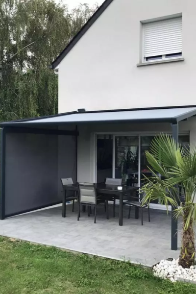 Pergola anthracite avec toile rétractable grise et store latéral sur terrasse, salon de jardin