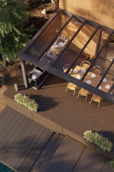 Vue plongeante pergola toit verre avec cuisine extérieure, table à manger et bardage bois