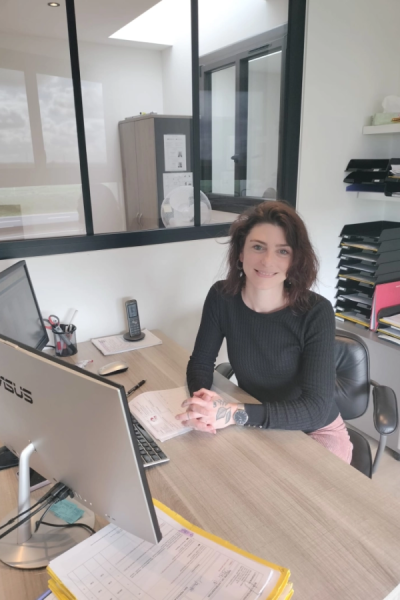 Femme souriante à un bureau avec ordinateur iiyama, téléphone et classeurs documents