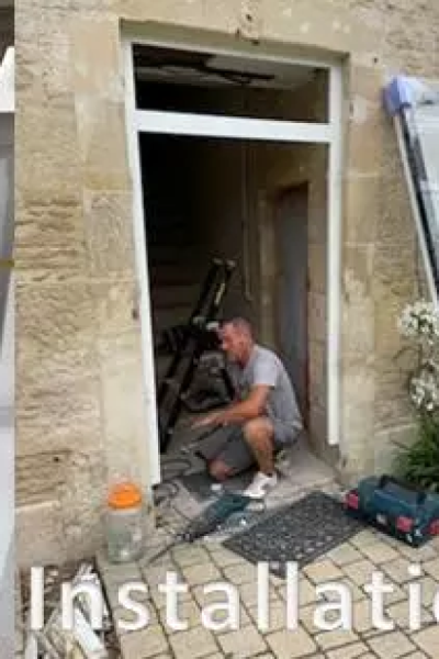 Ouvrier agenouillé pose huisserie blanche dans ouverture pierre, texte Installation en surimpression
