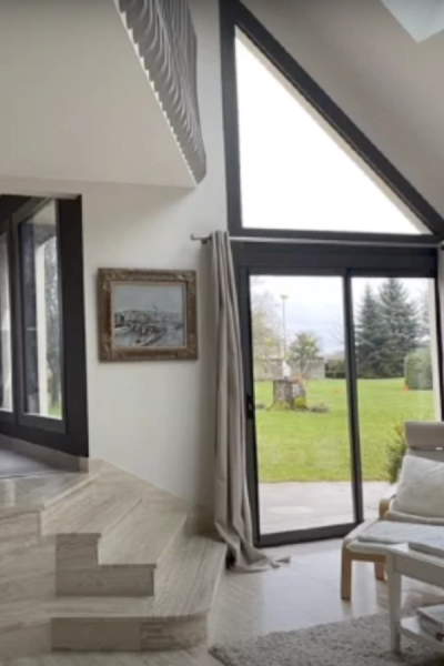 Baie coulissante et fenêtre triangulaire anthracite sous combles, vue jardin depuis salon