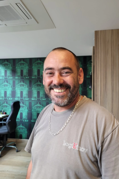 Collaborateur souriant t-shirt LogiKinov devant papier peint vert à motifs dans un bureau