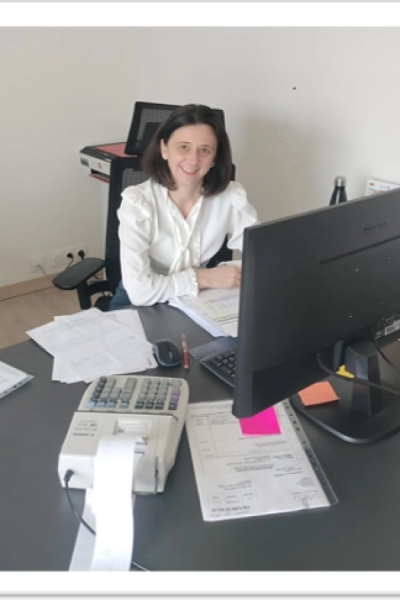Collaboratrice comptable souriante au bureau avec calculatrice imprimante et classeurs