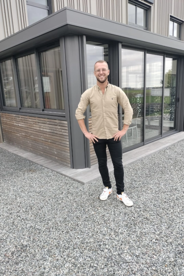 Technicien souriant lunettes devant extension alu gris, bardage bois et gravier