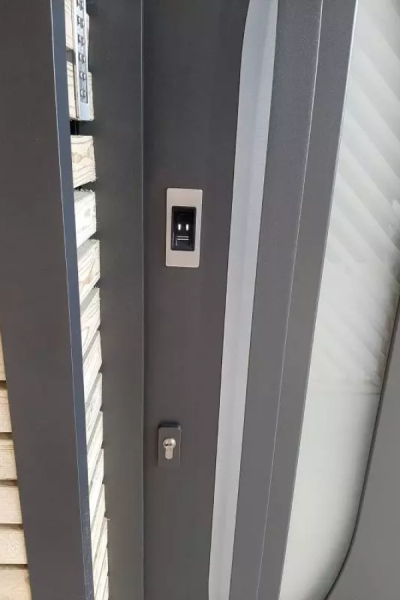 Gros plan porte anthracite avec lecteur empreinte, serrure et vitrage dépoli barres diagonales