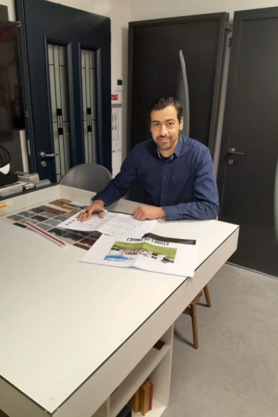 Conseiller au bureau vitré avec plans, nuancier sous verre et portes d'entrée en exposition