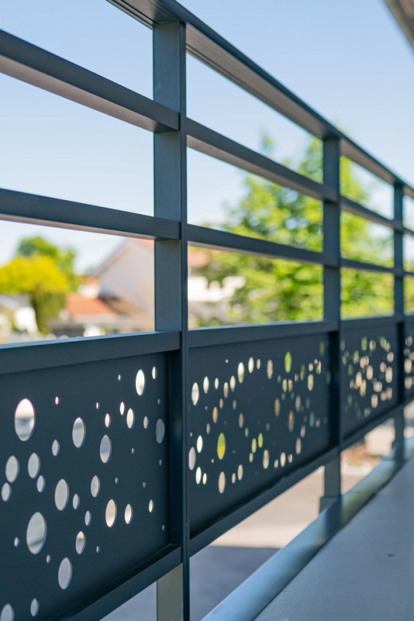Garde-corps anthracite à barres horizontales et panneau perforé bulles sur balcon ensoleillé