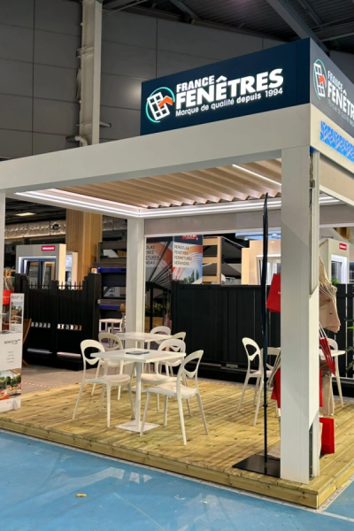 Stand France Fenêtres avec pergola bioclimatique blanche LED, lames orientables et tables blanches