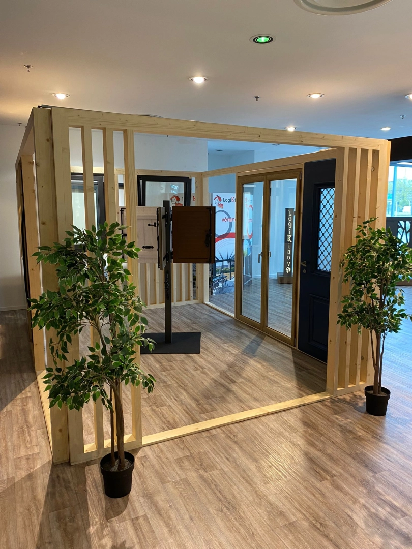 Stand bois clair avec porte bleue, baie vitrée bois et échantillons volets