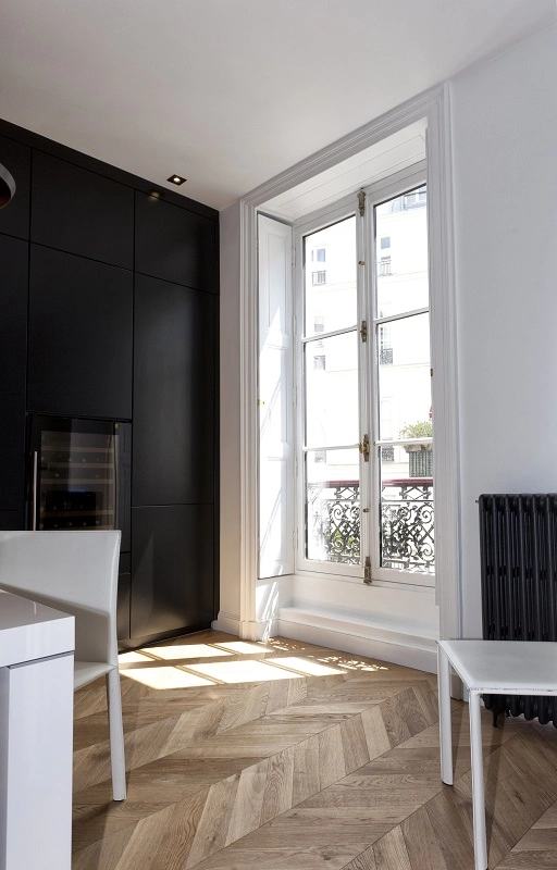 Porte-fenêtre blanche crémone dorée, balcon fer forgé et cuisine noire, ombres parquet