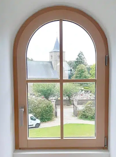 Fenêtre cintrée bois clair, vue clocher, cimetière et camionnette blanche