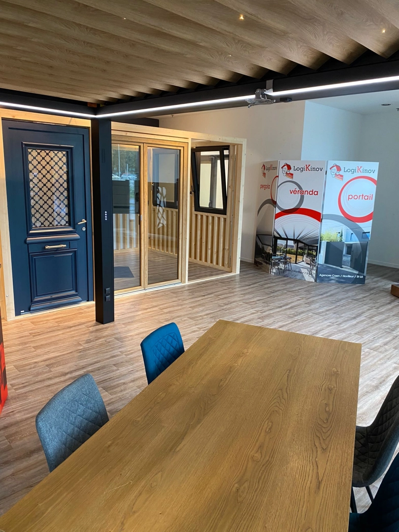 Showroom table bois, porte bleue, bannières Logo Logikinov pergola véranda portail