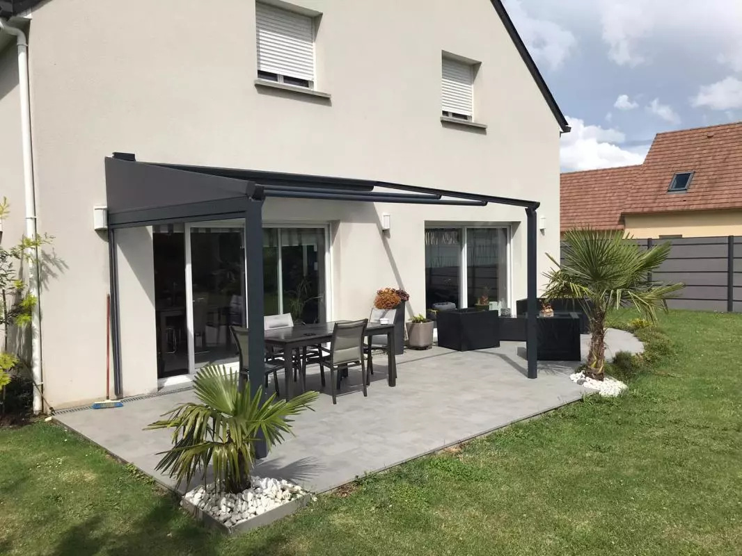 Pergola gris anthracite à toile rétractable sur terrasse dalles, salon et palmiers