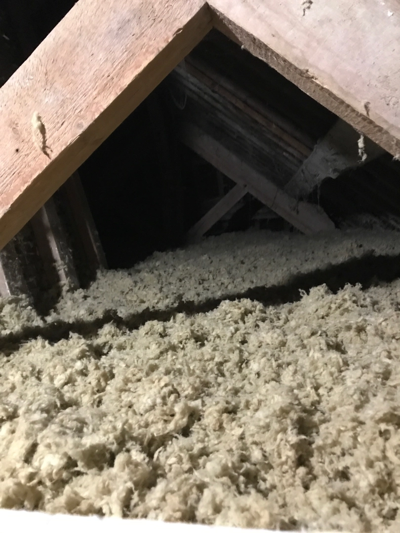 Combles avec épaisse couche isolant vrac gris-beige sous charpente bois