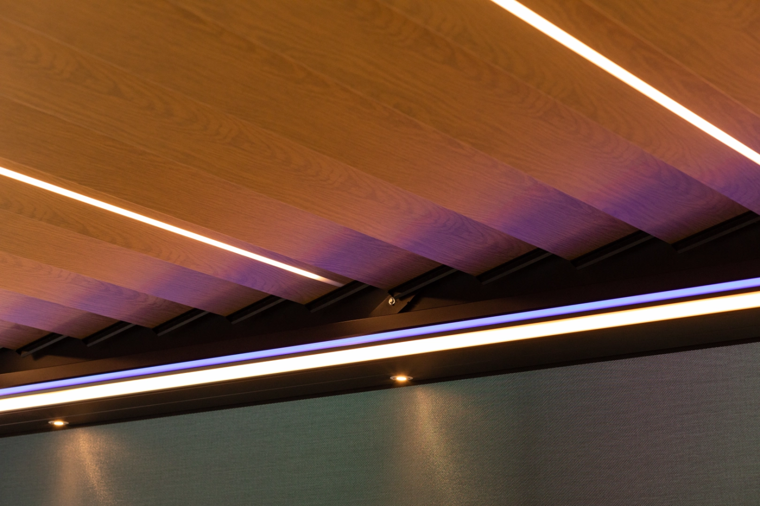 Gros plan lames bois clair pergola bioclimatique avec bandeaux LED chauds et froids