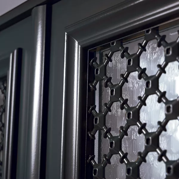 Gros plan grille noire croisillons sur vitrage martelé, cadre porte gris anthracite