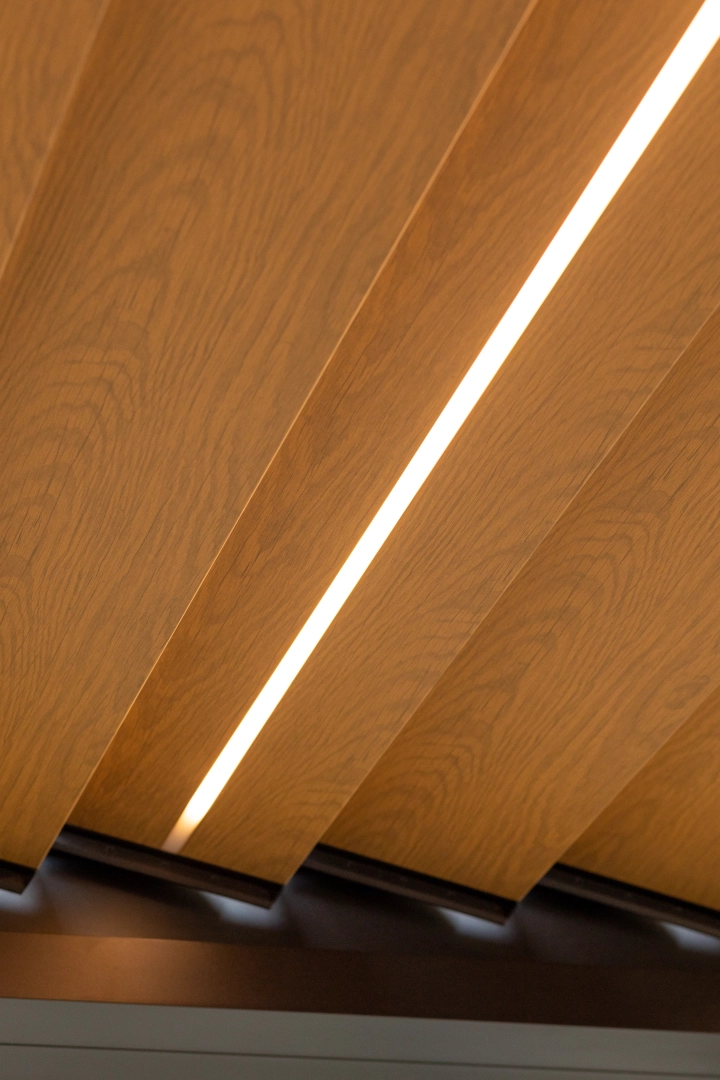 Gros plan lames bois pergola avec ruban LED allumé en diagonale