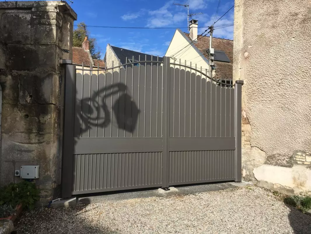 Portail double gris barreaux arrondis et soubassement plein entre murs en pierre
