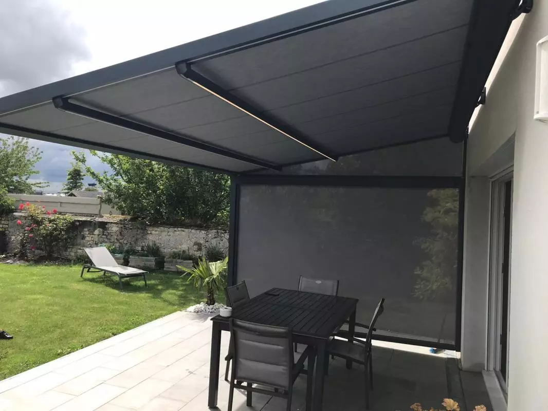 Store banne gris anthracite à LED et store latéral sur terrasse avec table et chaises