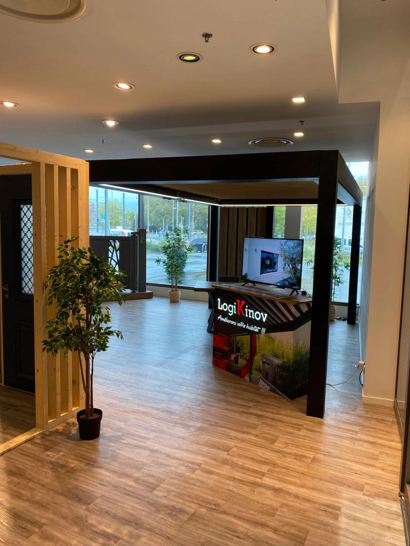 Showroom comptoir Logo Logikinov sous pergola noire LED, plantes et grandes vitres