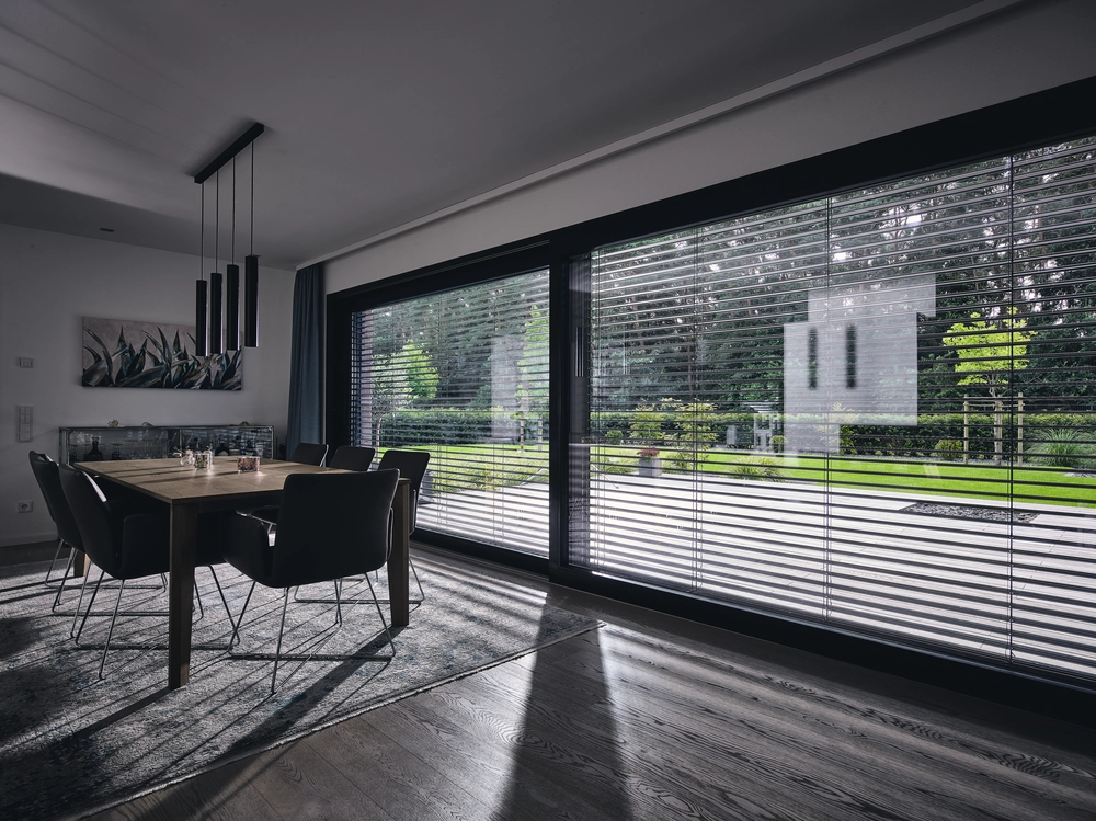 Salle à manger table bois, six chaises et brise-soleil orientables gris sur baie vitrée