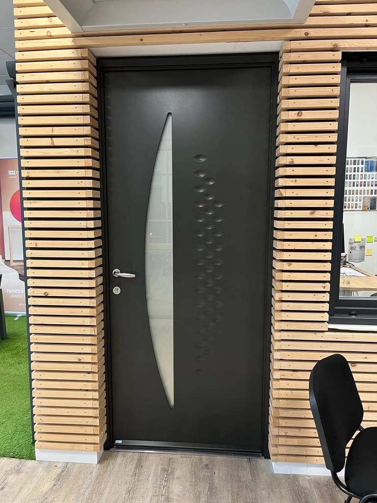 Porte anthracite vitre arquée dépolie et motif pastilles, mur tasseaux bois showroom