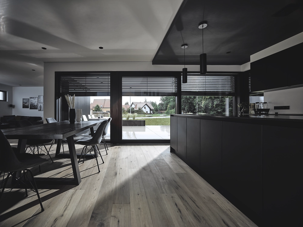 Cuisine noire, table bois et baies coulissantes stores lamelles noirs, ombres parquet