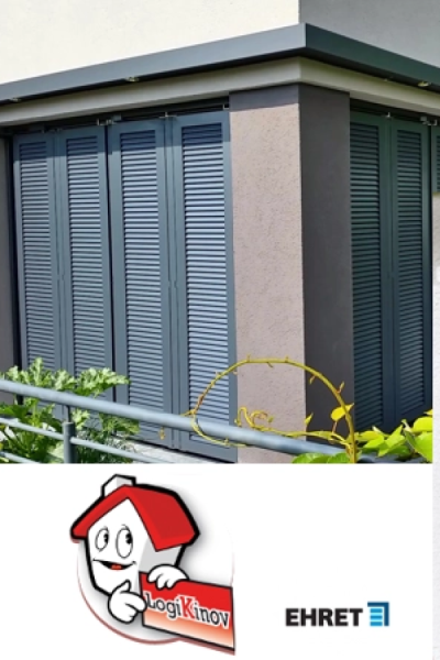 Volets pliants aluminium anthracite sur angle de façade avec logo EHRET