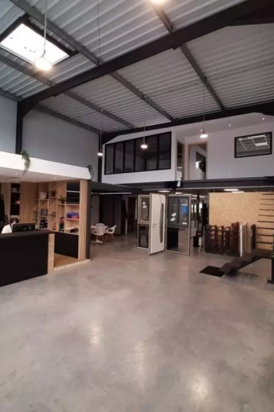 Showroom avec comptoir d'accueil, exposition portes et fenêtres, mezzanine verre style industriel