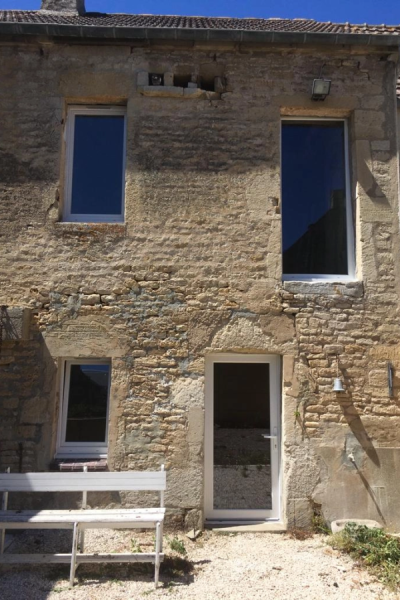Maison pierre avec fenêtres et porte PVC blanches neuves, banc blanc sur gravier