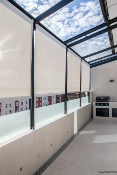 Pergola toit verre noir, stores verticaux crème, muret verre dépoli et plancha extérieure