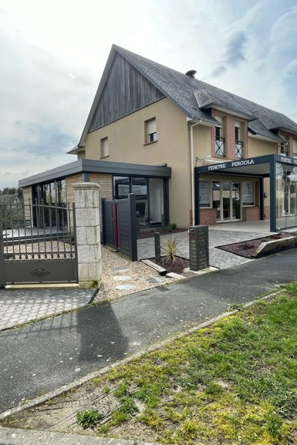 Showroom avec extension verre, enseigne FENETRE PERGOLA sur pergola noire et portails