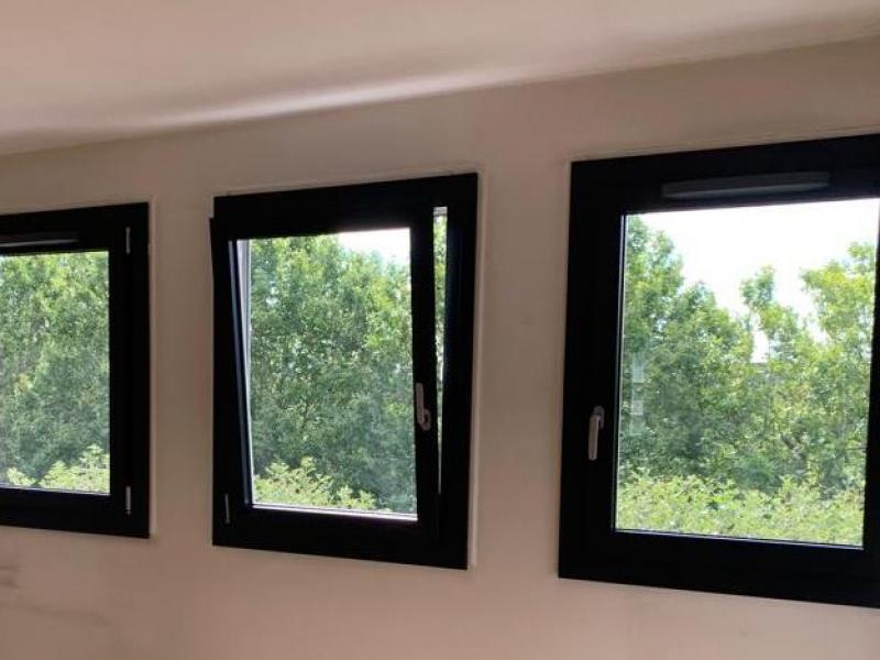 Trois fenetres noires alignees, l une en position oscillo-battante, vue sur le jardin