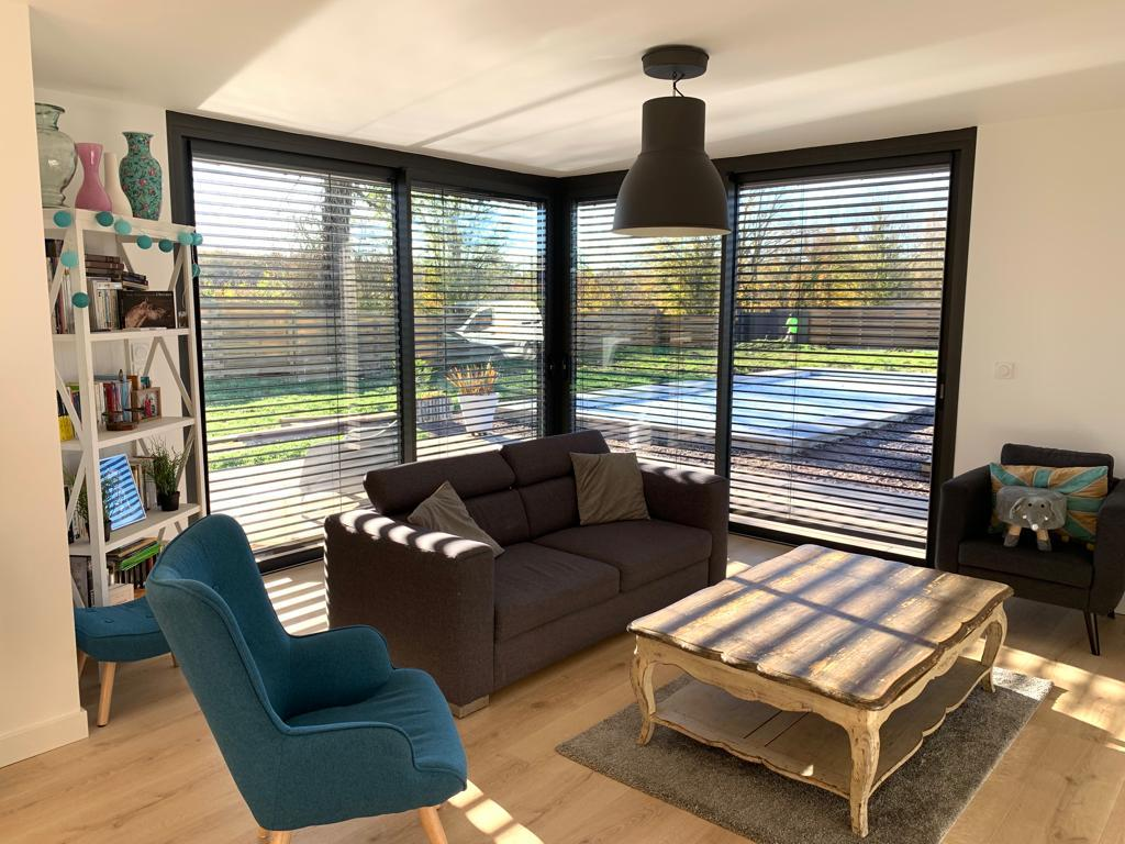 Salon avec BSO noirs sur baie d'angle, fauteuils velours, ombres, vue jardin et piscine