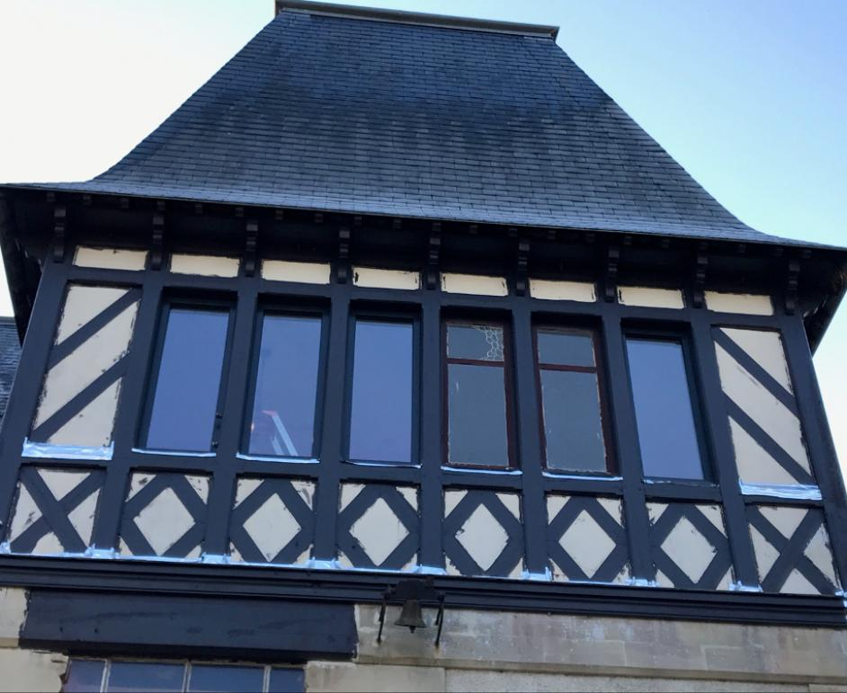 Façade colombages et ardoise, rangée de fenêtres étroites cadres sombres sous ciel bleu