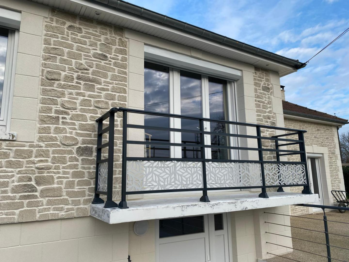 Garde-corps noir alu avec panneaux découpés motif feuilles sur balcon pierre