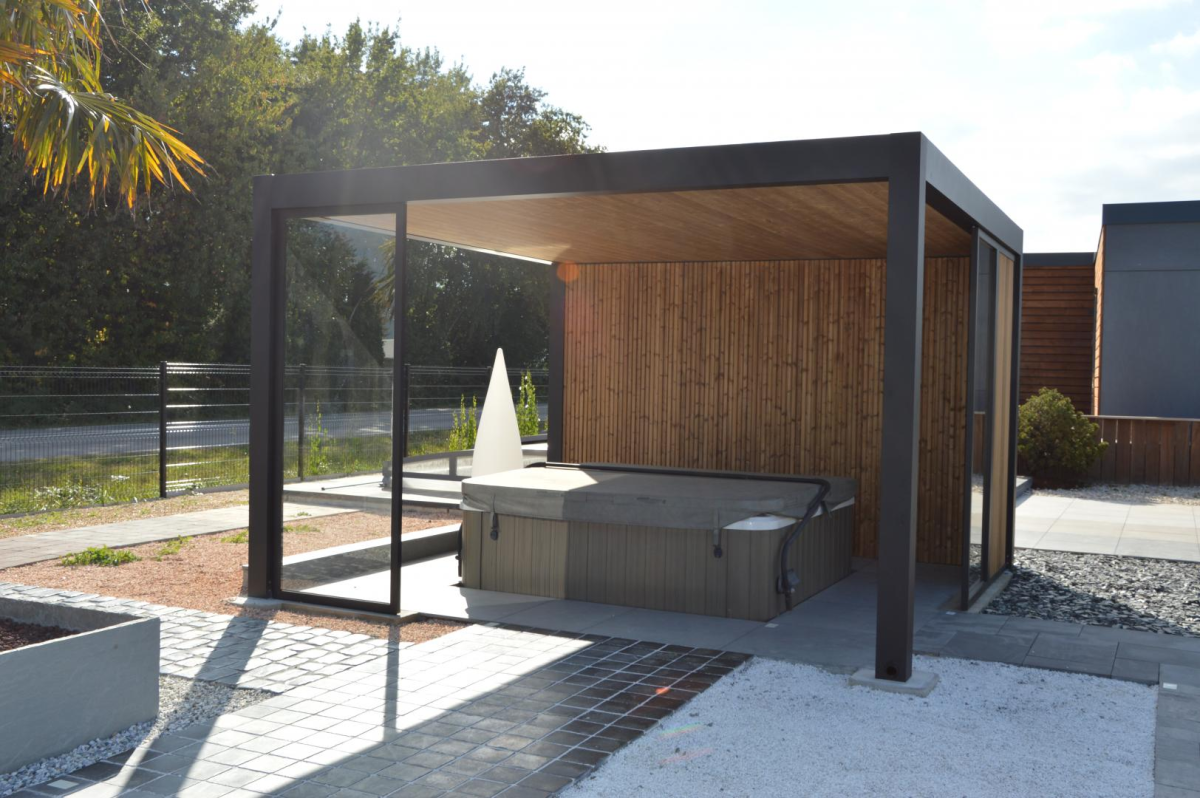 Pergola noire anthracite abritant un jacuzzi, lambris bois clair et paroi vitrée coulissante