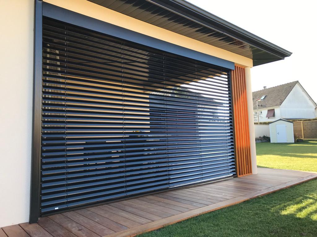 BSO anthracite incliné sur grande ouverture, terrasse bois, lames bois orange à droite