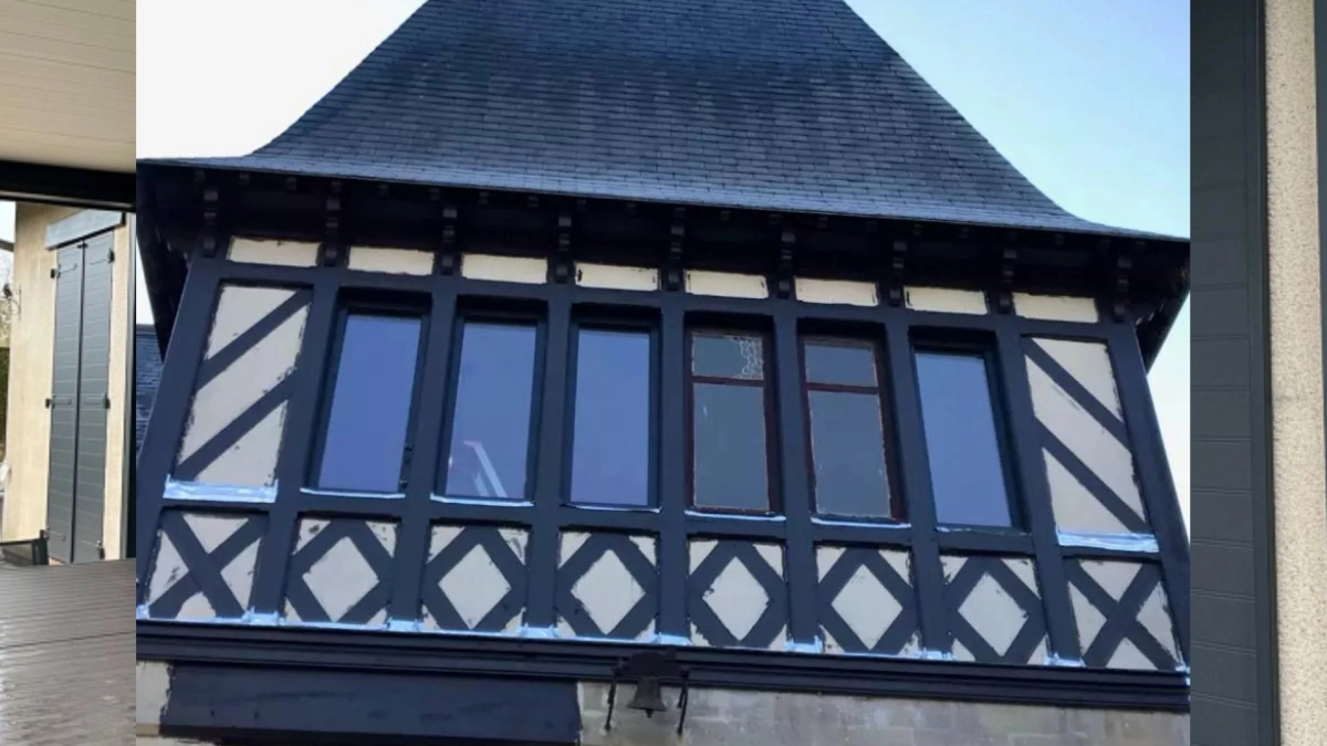 Rangée six fenêtres verticales cadres sombres sur colombages, toiture ardoise