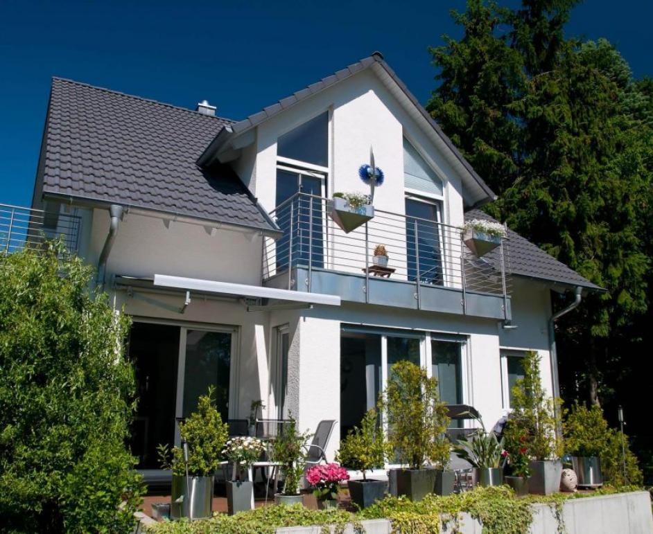 Maison blanche deux niveaux, baies gris foncé, balcon inox et jardinières fleuries