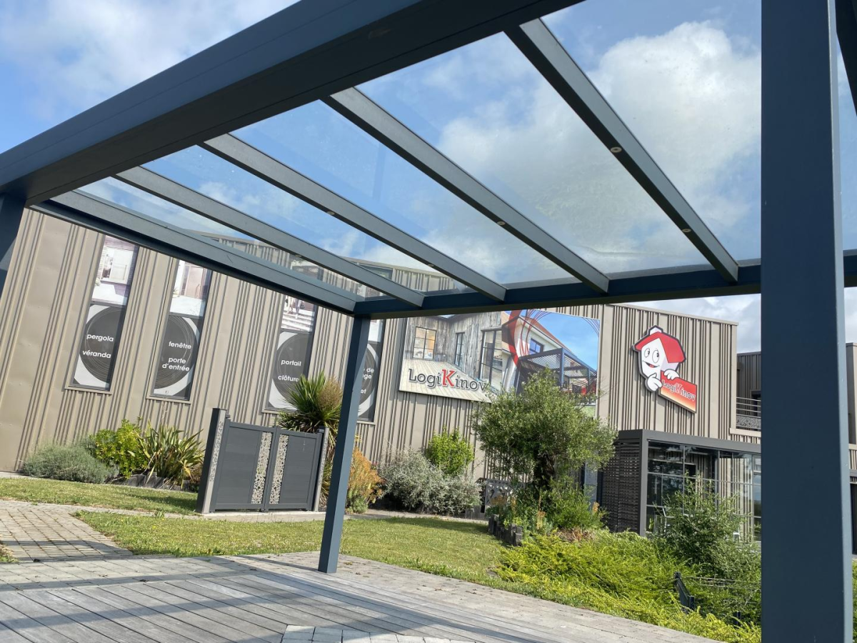 Pergola toit vitre, batiment Logikinov et bannieres produits visibles en arriere-plan