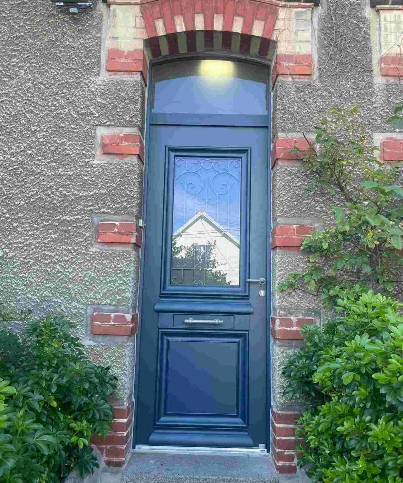 Porte bleu marine, imposte cintrée, vitrail ferronnerie et panneau bas, mur pierre grise
