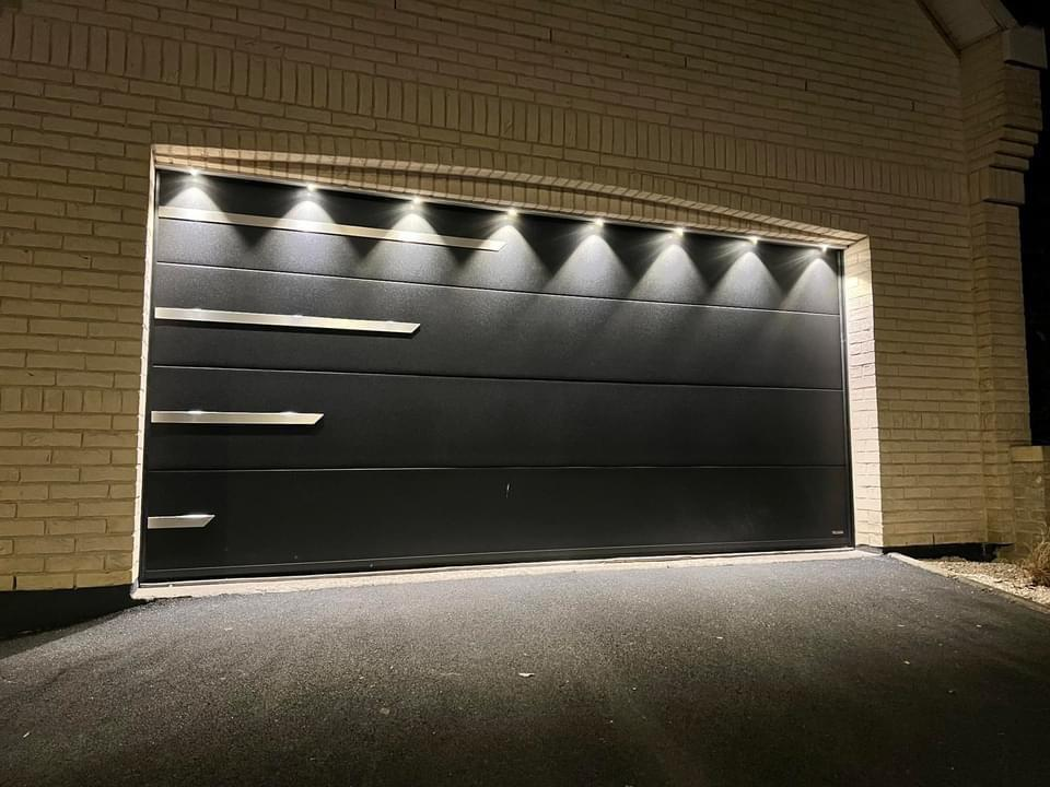 Porte garage sectionnelle anthracite de nuit, inserts inox décalés, spots LED encastrés