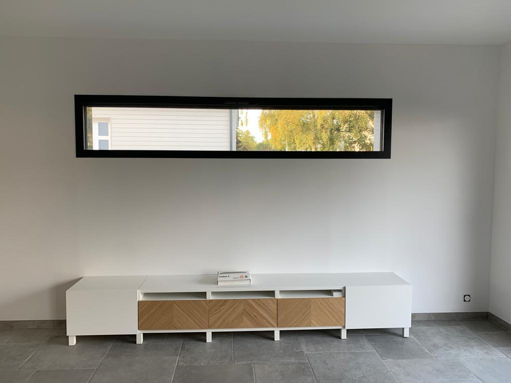 Fenêtre fixe horizontale cadre noir au-dessus d'un meuble TV bois chevron sur carrelage gris