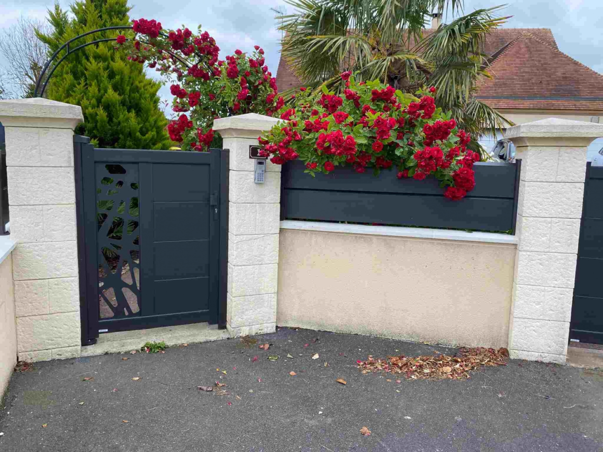 Portillon anthracite motif découpé et cloture lames, rosier rouge sur piliers pierre