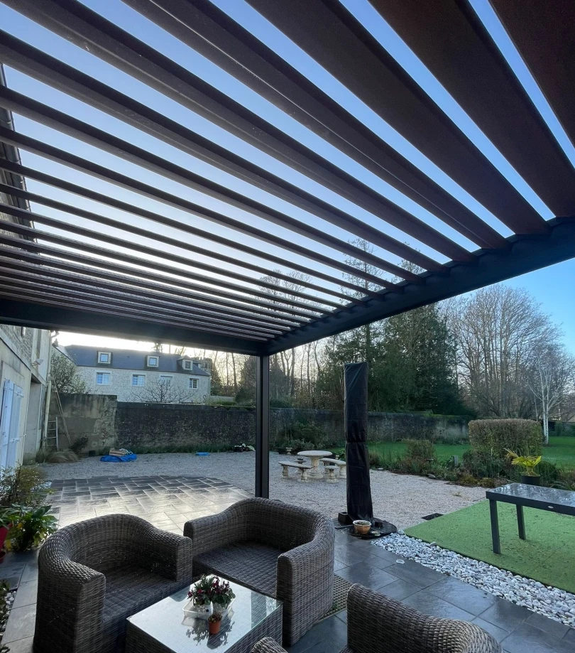 Pergola a lames orientables anthracite au-dessus d un salon de jardin en resine grise