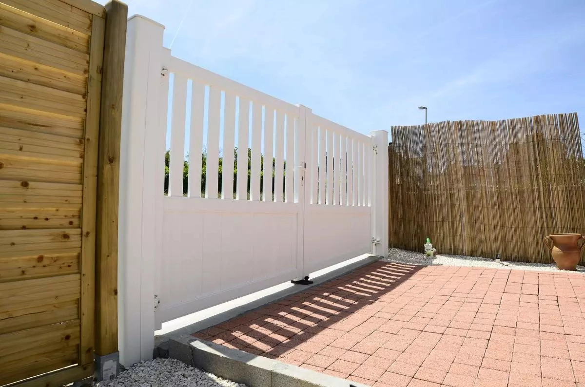 Portail battant blanc semi-ajouré barreaux verticaux entre canisse et claire-voie bois