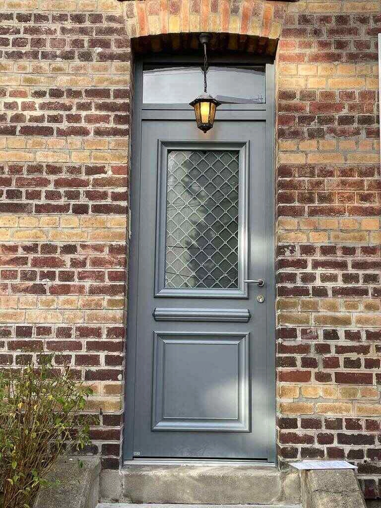 Porte d entree grise imposte vitree, grille losange et mur briques rouges et jaunes