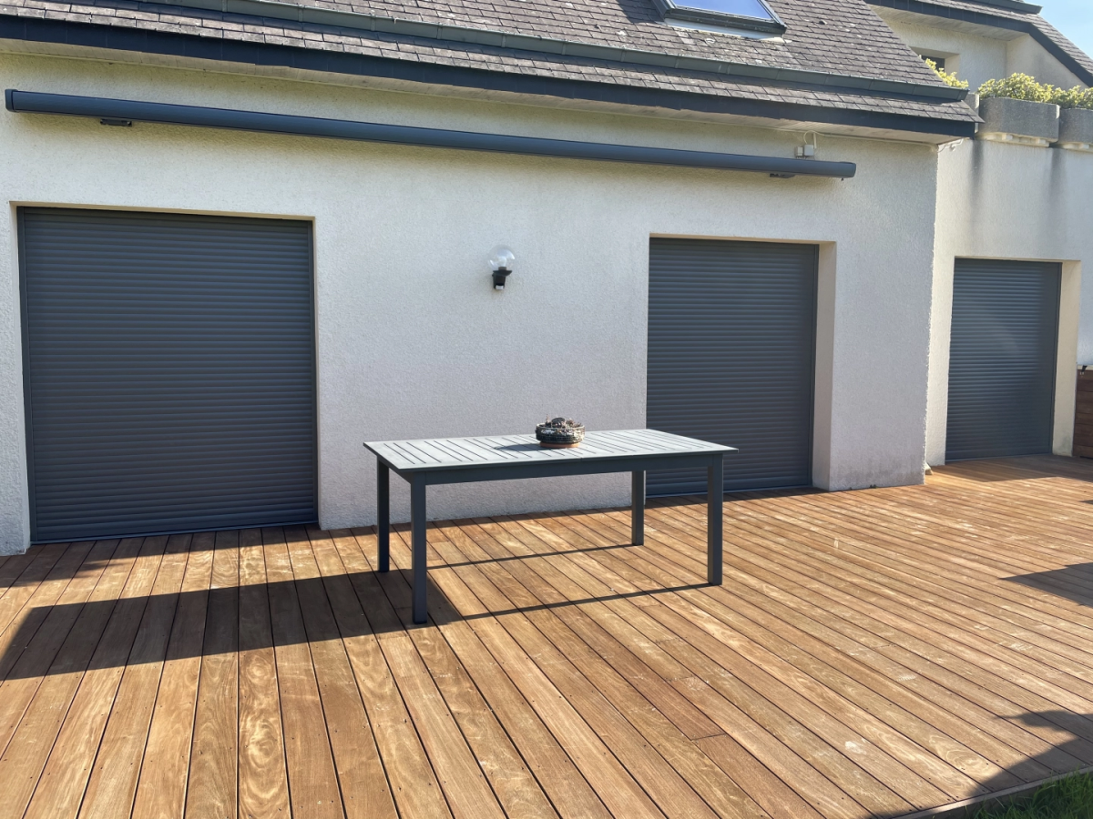 Façade blanche, volets roulants anthracite fermés, coffre store banne, terrasse bois
