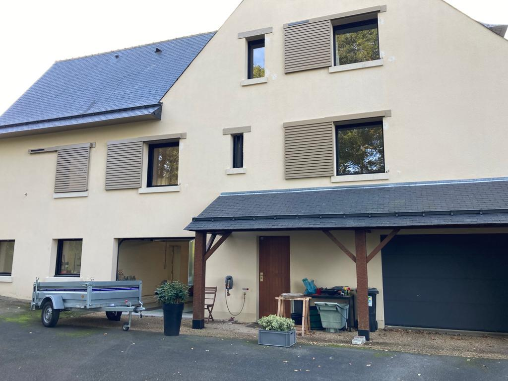 Maison beige toit ardoise avec volets coulissants taupe à lames sur plusieurs baies d’étage